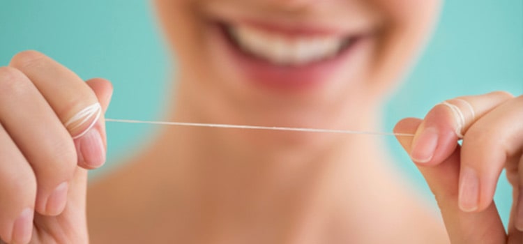 una chica muestra un segmento de hilo dental