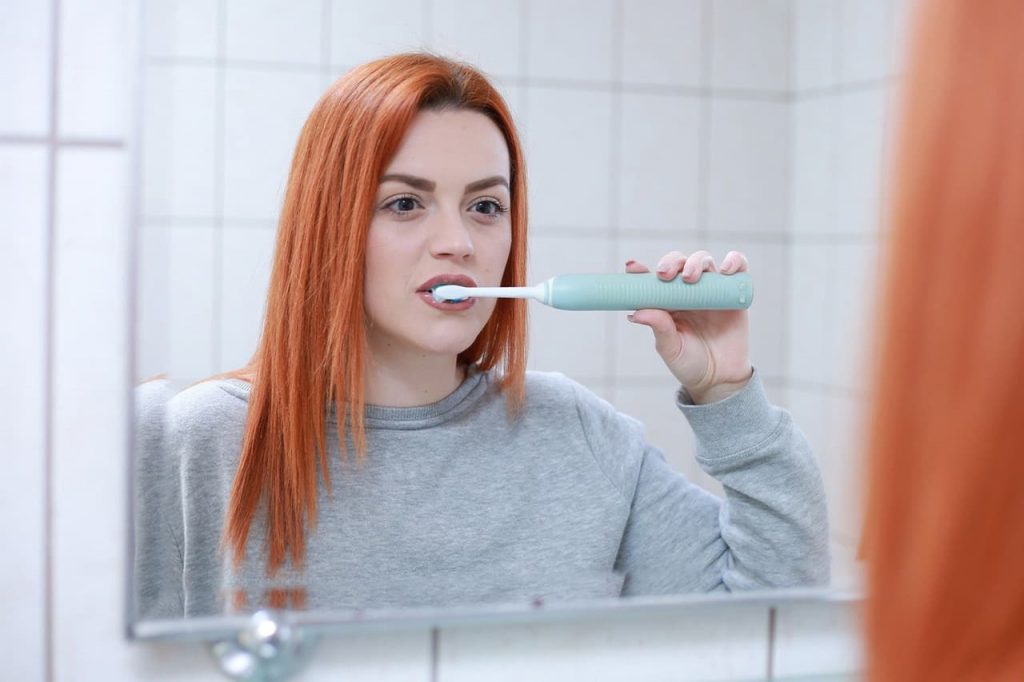 una chica se cepilla los dientes frente al espejo